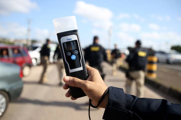 Hand holding a breathalyzer device.