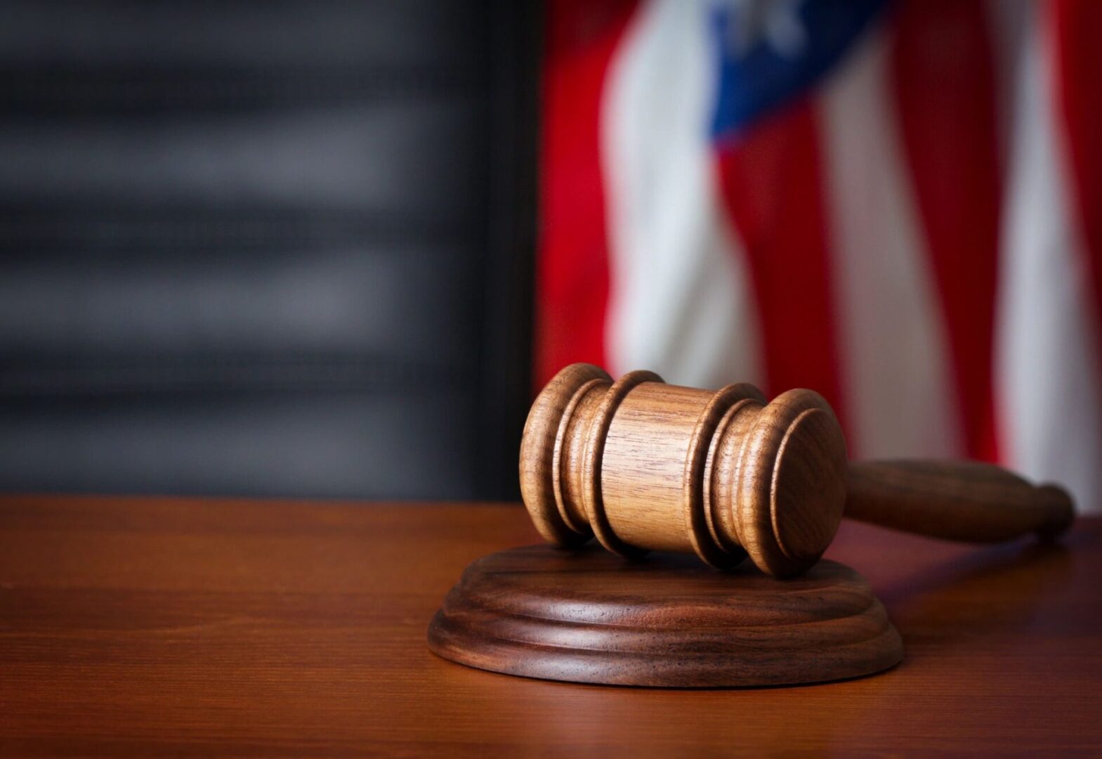 Wooden gavel on sound block, American flag.