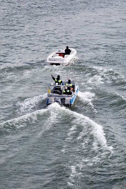 Police boat intercepts motorboat on water.